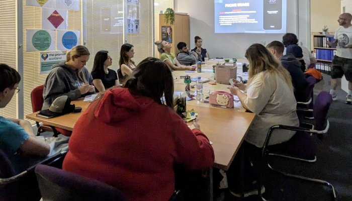 Young people sitting around the table, learning about our intro to customer services programme
