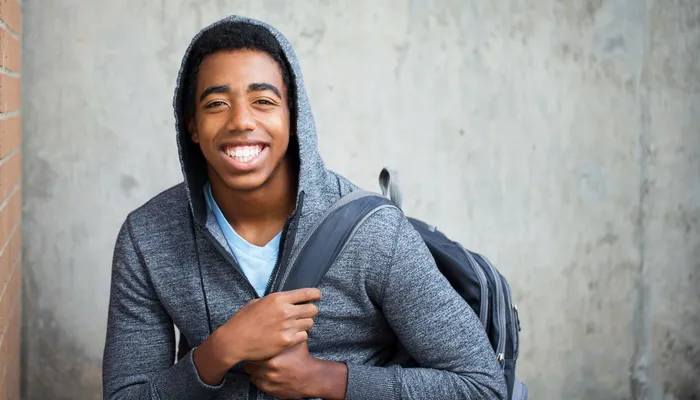 Young teenage boy with big smile wearing backpack and hoodie.jpg