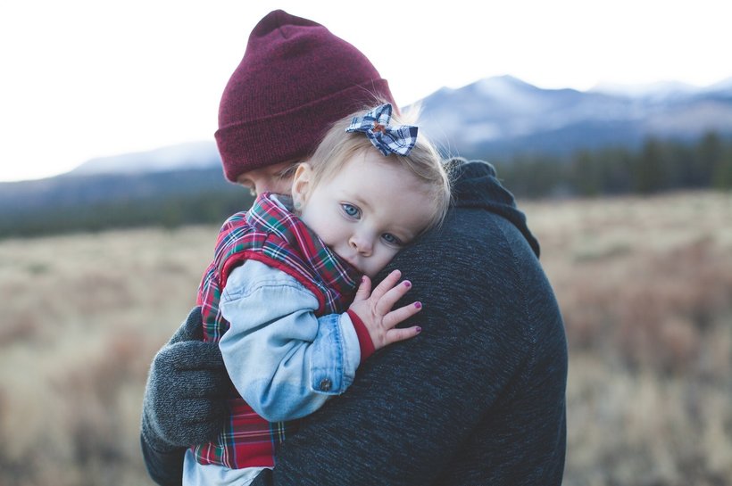Young toddler with painted nails and father hugging outdoors