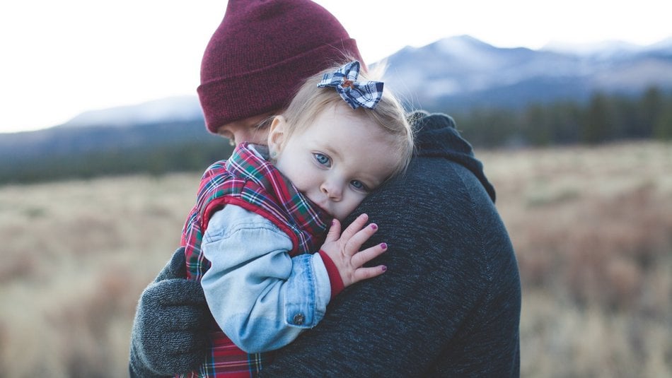 Young toddler with painted nails and father hugging outdoors