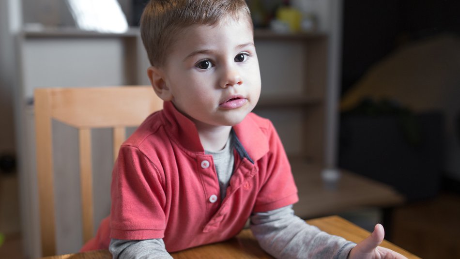 Young worried boy sitting at table with empty plate