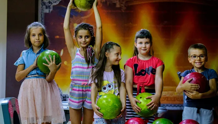 Group of children bowling with friends