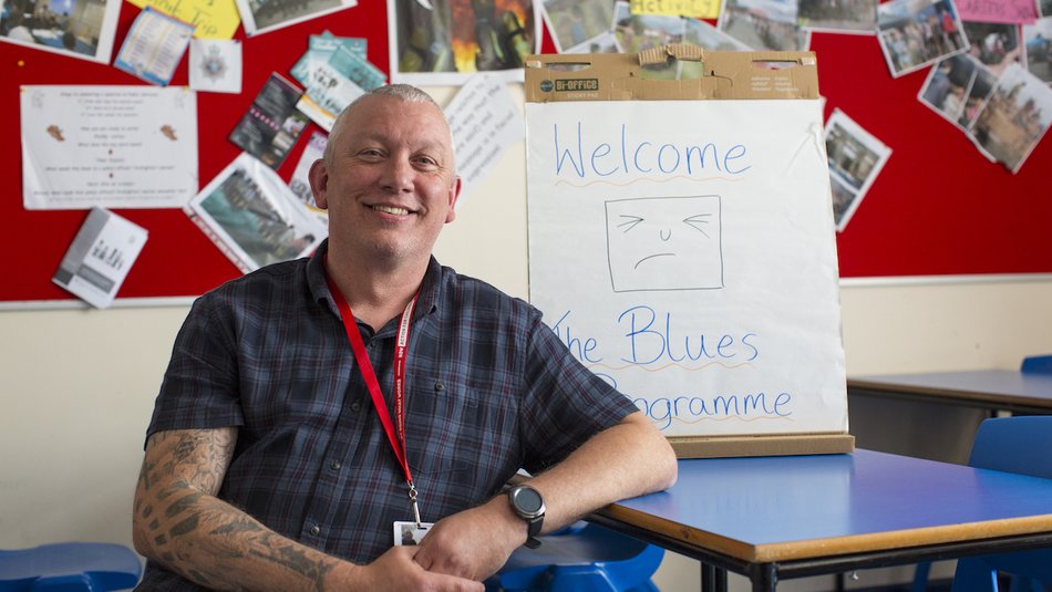 man in front of blues programme sign.jpg