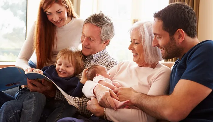 Multigenerational family huddled around a toddler, reading him a book.