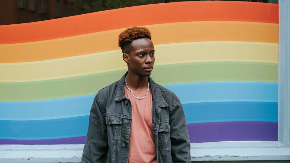 Black person in front of LGBT flag
