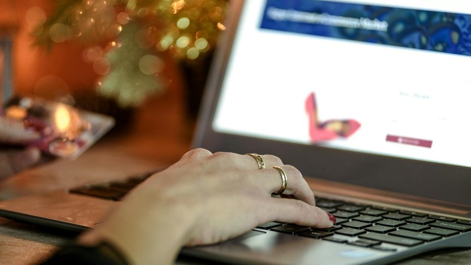 Woman's hand using laptop with blurred screen and festive lights behind