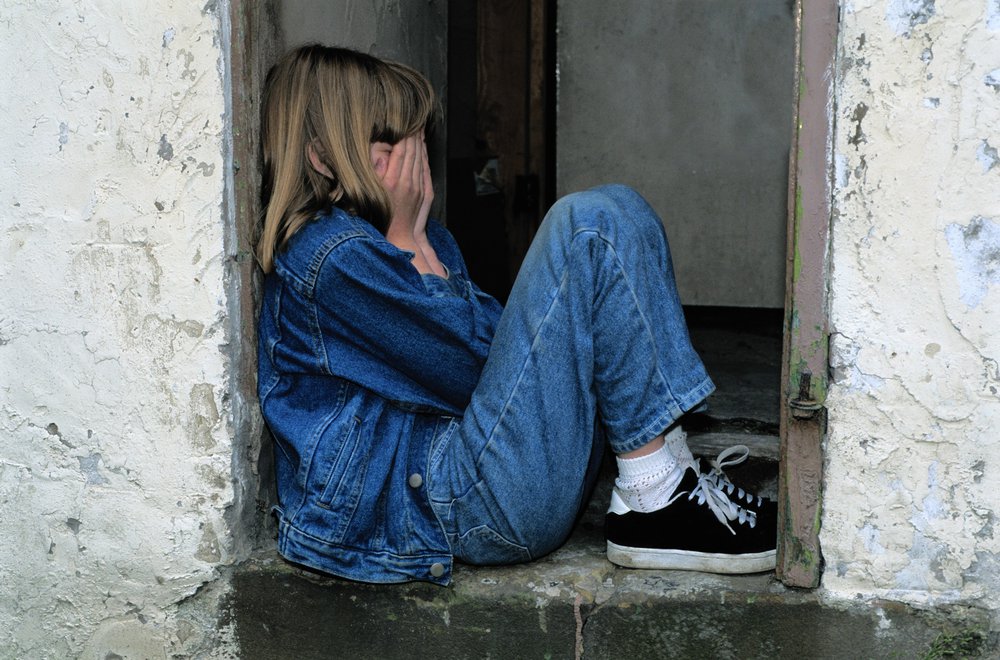 Young girl covering her face in her hands