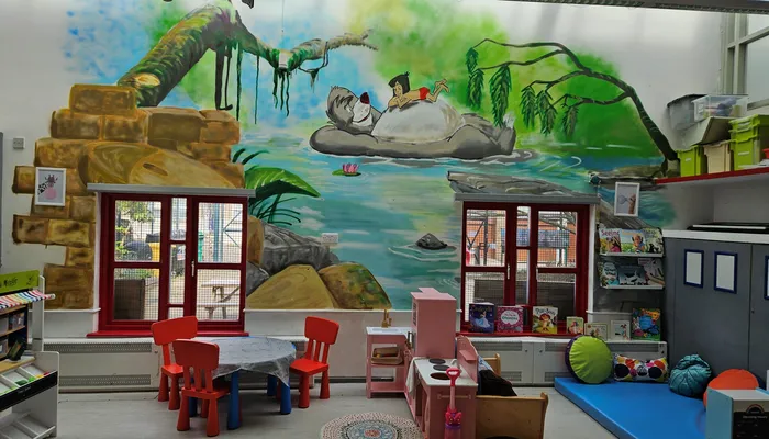 A playroom with home corner, reading area and mural of the Jungle Book