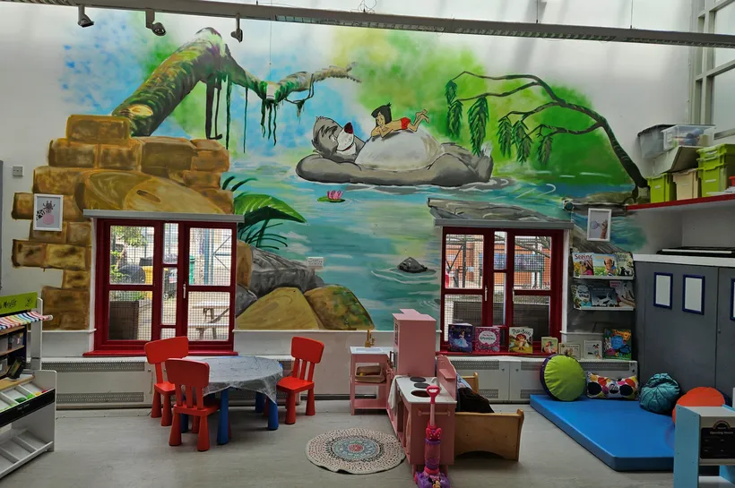 A playroom with home corner, reading area and mural of the Jungle Book