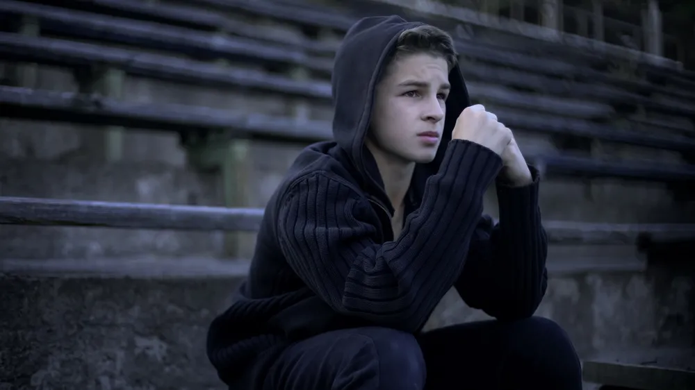 Boy with hood sat on step