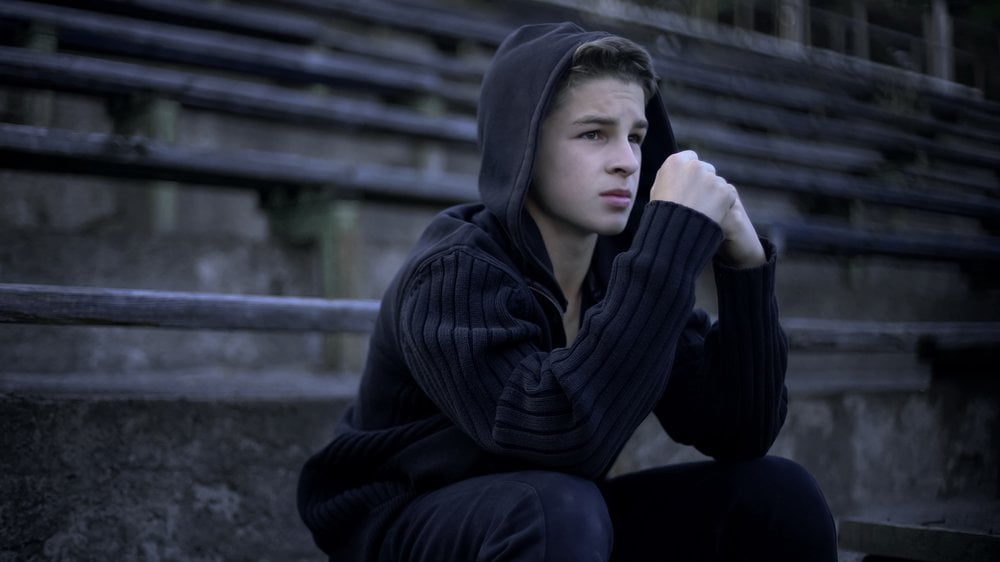 Boy with hood sat on step