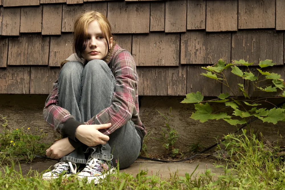 Teenage girl outside hands round knees.jpg