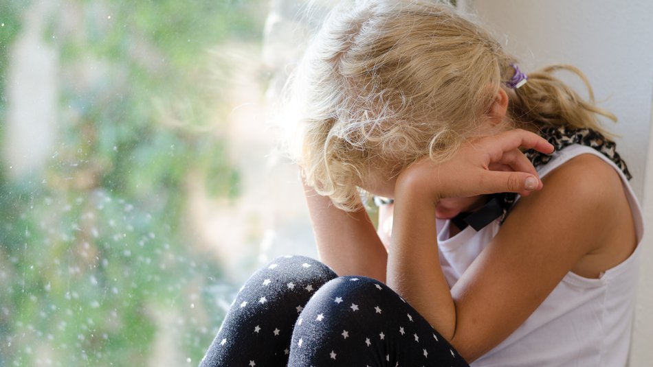 Young  girl sitting by the window and crying