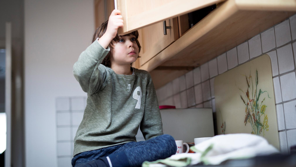 young boy looking in cupboard.png